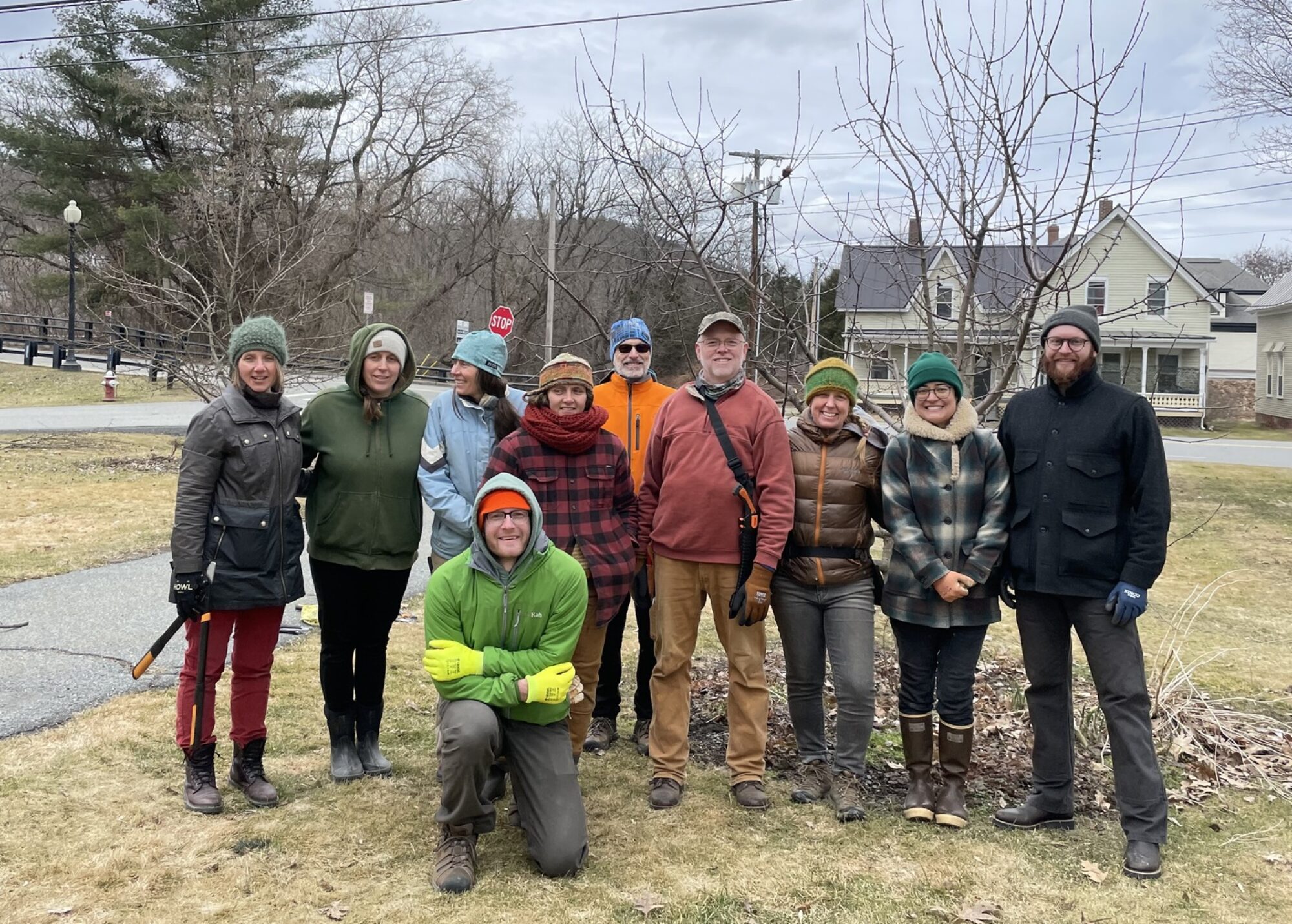 A group of volunteers poses in front of a pear tree they have just pruned.